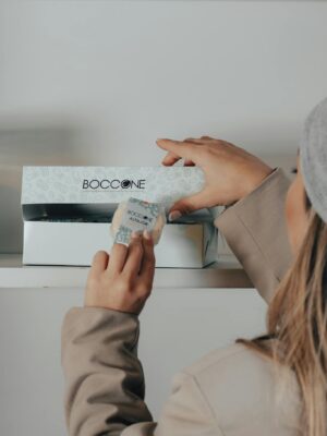 A woman opening a Boccone box in a store setting, focusing on packaging.